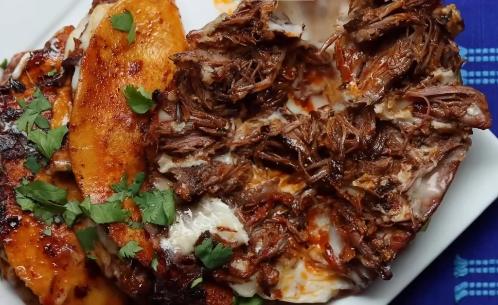 Authentic birria tacos with consomé dipping sauce on a wooden board