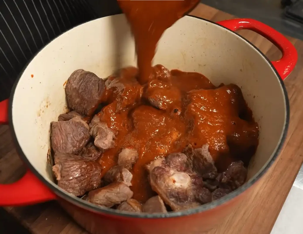 Beef simmering in a rich red chile sauce for birria