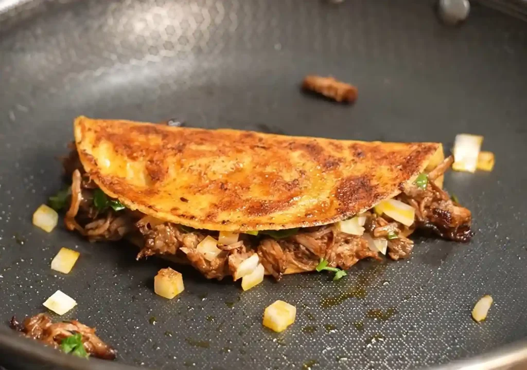 Crispy birria tacos filled with tender shredded beef and melted cheese